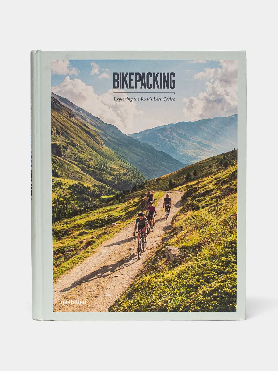 Bikepacking book cover shows photograph of cyclists riding through a mountain range on a dirt trail.