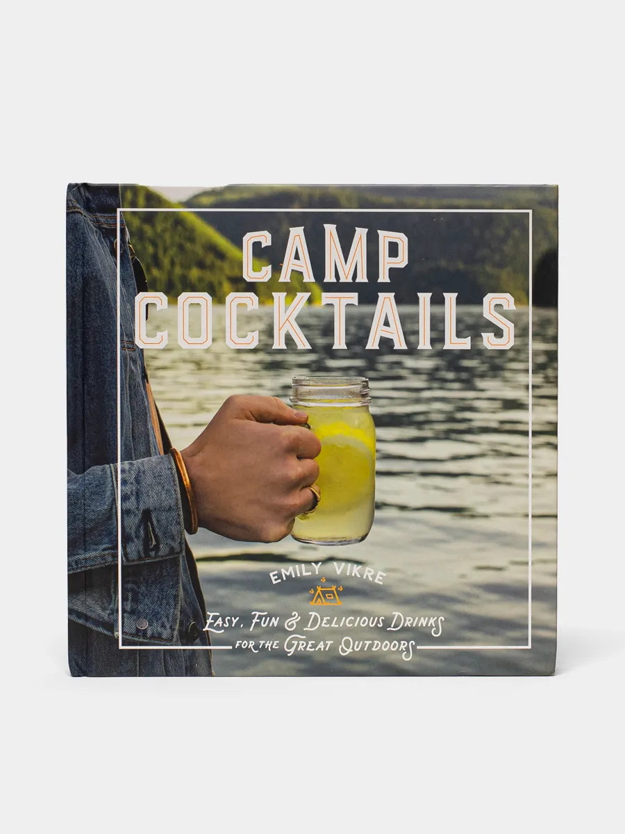 Camp Cocktails front cover depicts a person holding a cocktail glass with a lake in the background