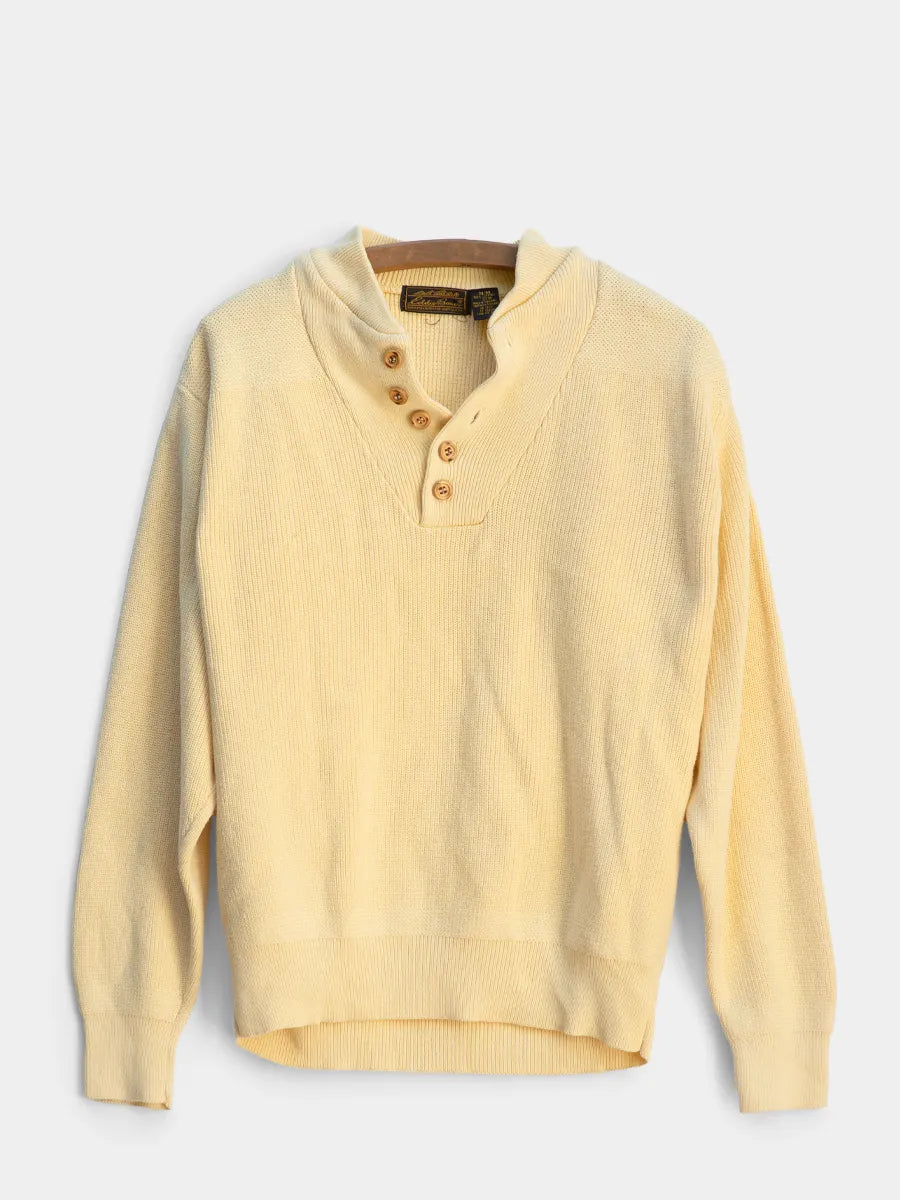 Yellow sweater with button details on a light gray background
