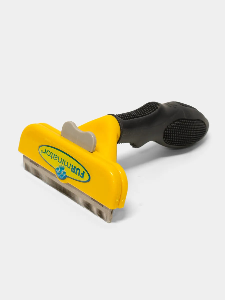 Pet grooming brush with yellow handle and black bristles on a white background