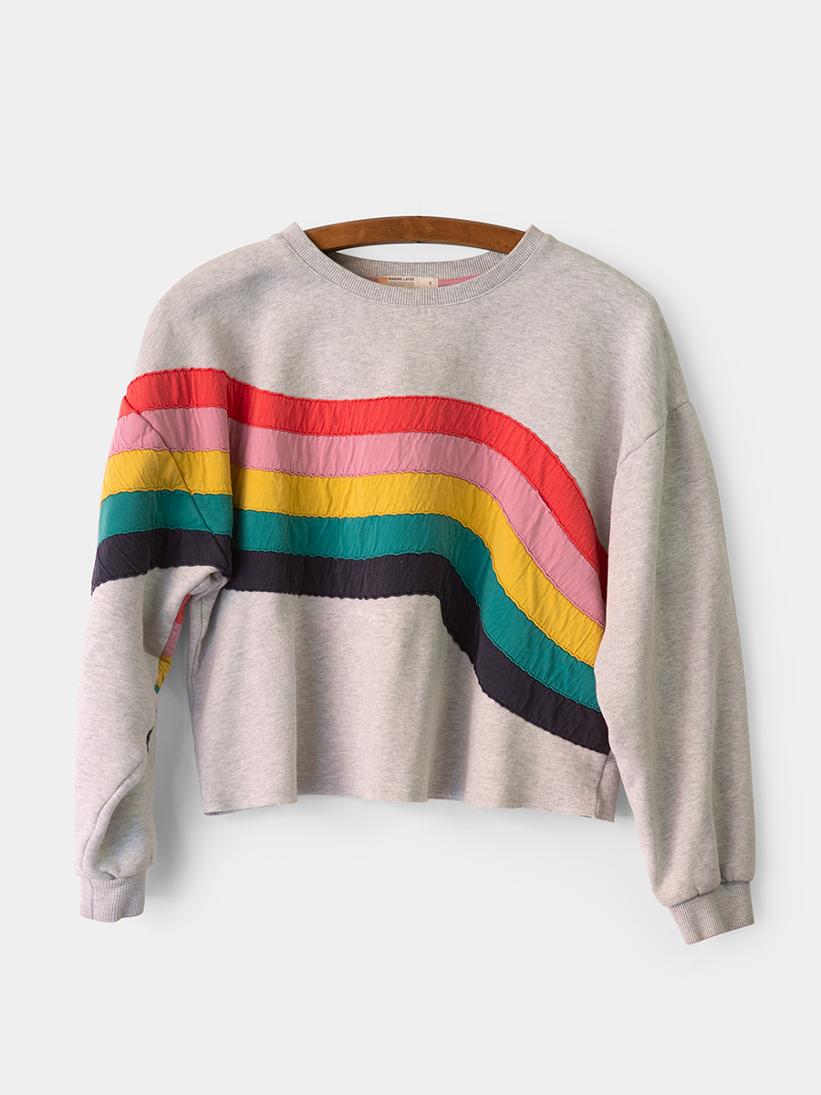 heather grey marine layer sweatshirt with a rainbow wave graphic across the body and right sleeve on a vintage wooden hanger.