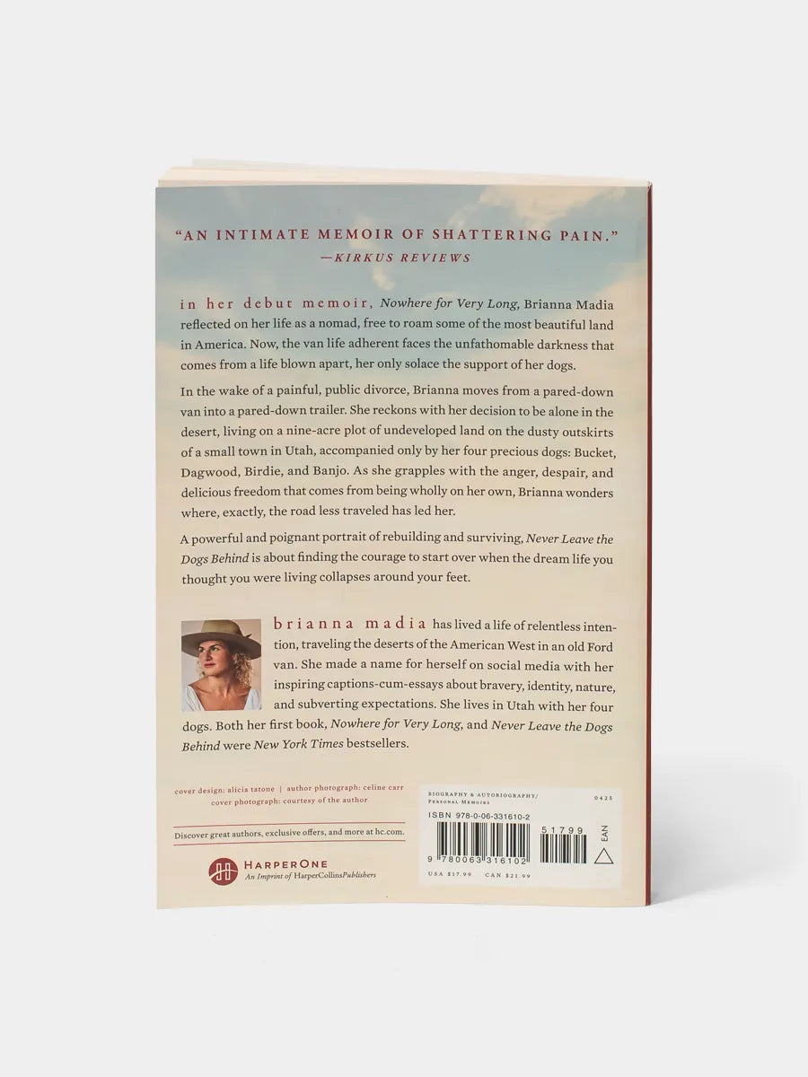 Back cover of Never Leave the Dogs Behind. A short description captures the heart of the memoir: a raw account of trading a nomadic van life for an even barer trailer existence on the edge of the desert. The copy emphasizes survival, solitude, and the grounding presence of four loyal dogs. Includes author bio and publisher details.