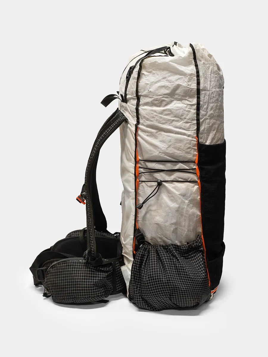 Side view of Hyperlite Mountain Gear Unbound 55 ultralight backpack in white and black with orange trim, showing padded straps and multiple pockets