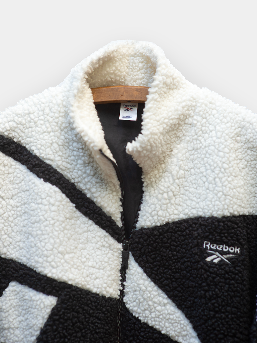 Black and white fleece jacket with Reebok logo on a light gray background