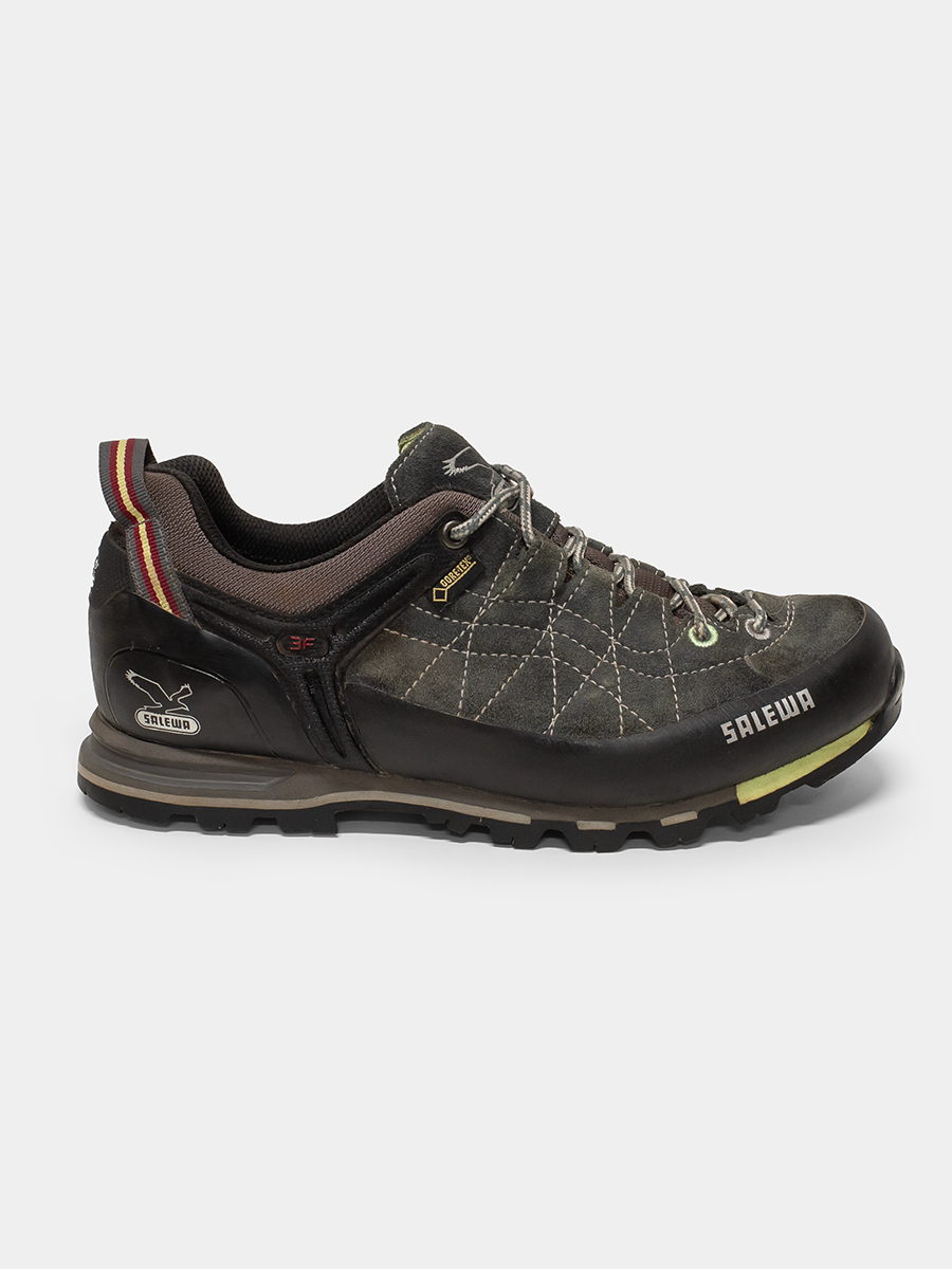 A Salomon G1000 hiking shoe in dark brown and black, featuring a textured synthetic leather upper, lace-up closure, and a rugged sole, shown against a light gray background.