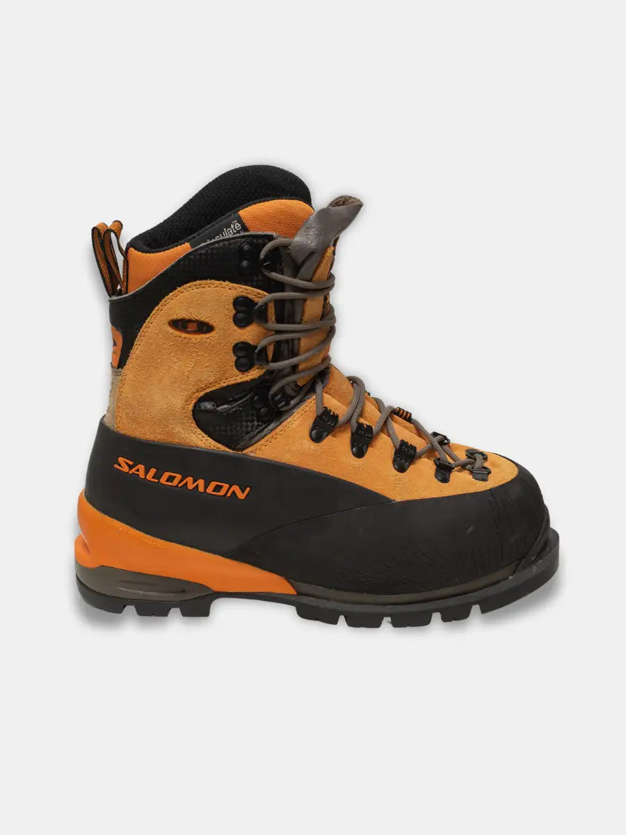 Side view of Salomon Pro Thermic women’s mountaineering boots in orange and black with rubber rand and removable liner, photographed on white background.