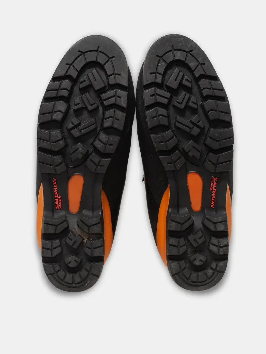 Sole view of Salomon Pro Thermic women’s mountaineering boots in orange and black with rubber rand and removable liner, photographed on white background.