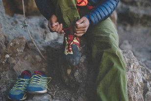 climber sitting on rock while tying shoe laces