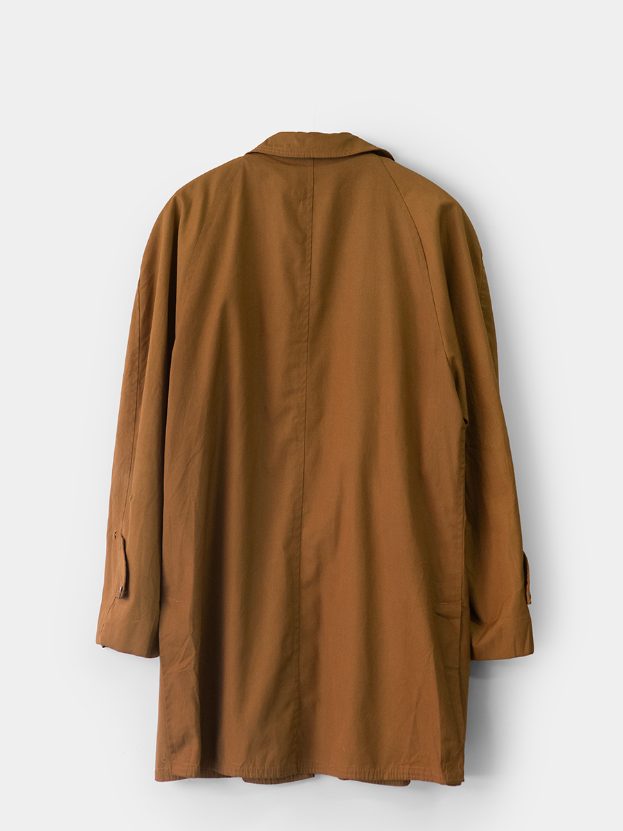 back view of vintage mid length trench jacket in warm tobacco color on a white ground.