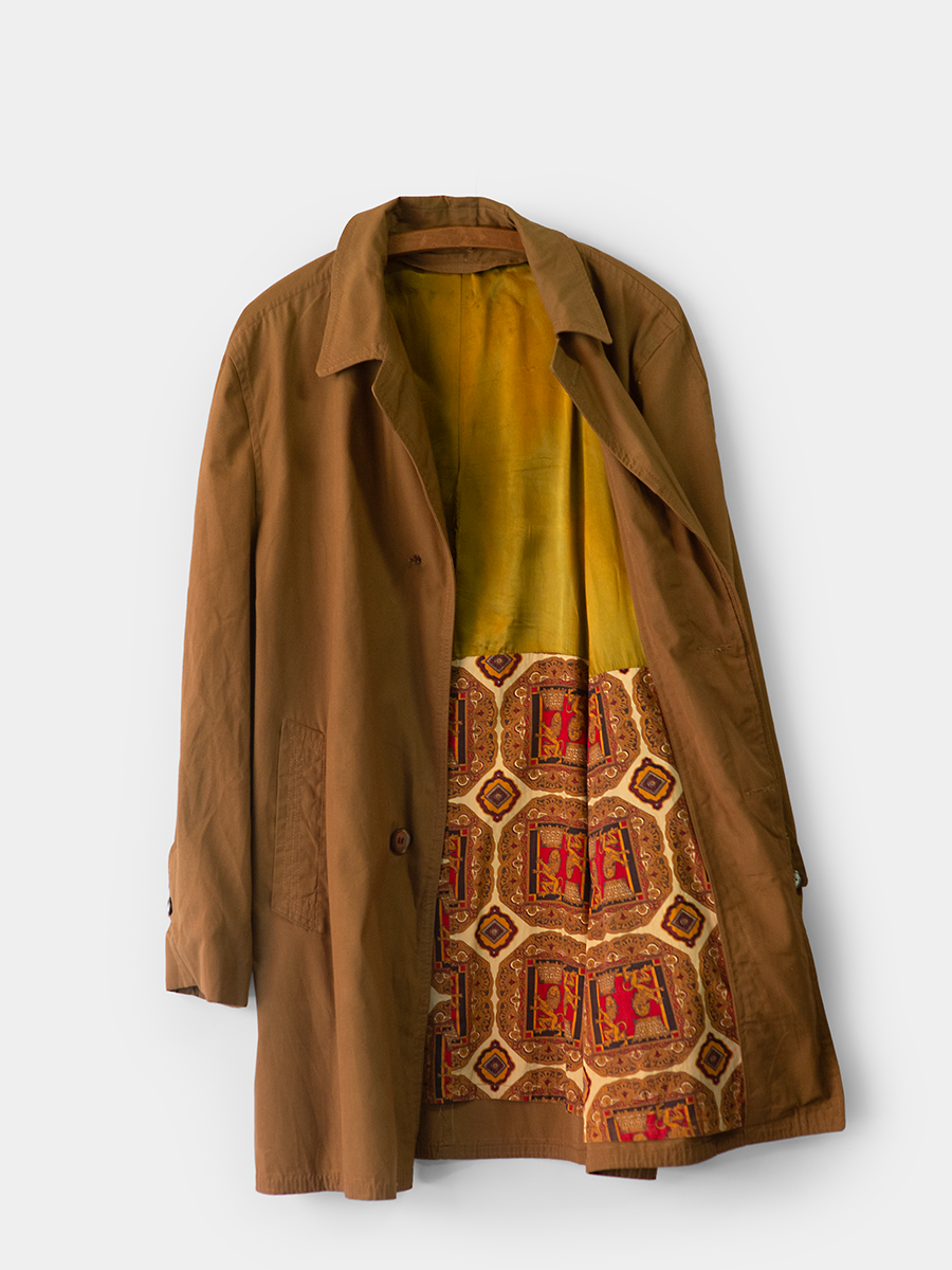 Vintage Mid Length Trench with a retro patterned lining on a white background hanging on a vintage wooden hanger. Inner Panel View.